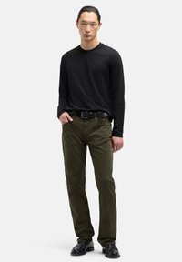 Czarna koszula z długim rękawem, oliwkowozielone spodnie, czarny pasek i czarne buty. Elegancki, dopasowany krój z minimalną ilością detali.