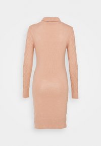 Robe tricotée rose pâle avec un col côtelé, des manches longues ornées d'un motif torsadé, et une silhouette ajustée, se terminant juste au-dessus du genou.