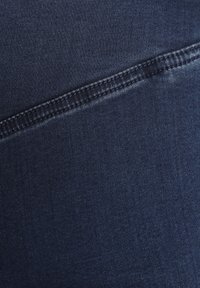 Dunkelblauer Denim-Stoff mit einer glatten Textur, der eine diagonale Naht und kontrastierende Nähte entlang des Randes aufweist.