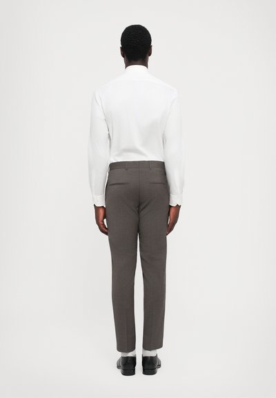 Cămașă albă cu mânecă lungă asociată cu pantaloni gri cu model. Pantalonii au un croi elegant și două buzunare la spate. Pantofii negri completează ținuta.
