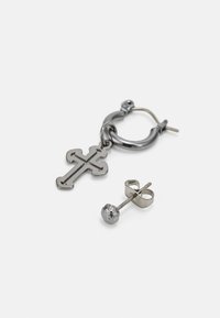 Sort metal hoop ørering med et kors vedhæng og en sølv stud ørering med en tekstureret sfærisk detalje. Begge har et minimalistisk design.