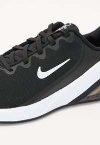 Scarpa sportiva nera con parte superiore in mesh testurizzato, logo Nike bianco e suola in gomma con design curvo e dettagli sottili.