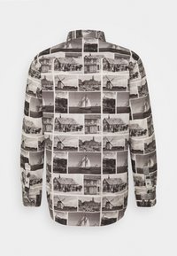 Kortärmad skjorta med ett collage av svartvita fotografier. Tillverkad av lättviktig tyg, har den en klassisk krage och knäppte ärmslut.