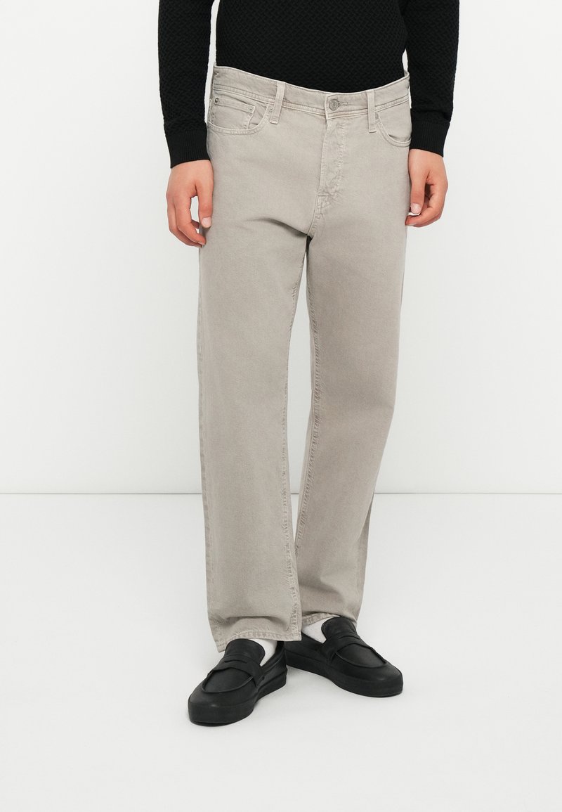 Light gray jeans with a straight fit, denim material, five-pocket design, and contrasting stitching, paired with black slip-on shoes.