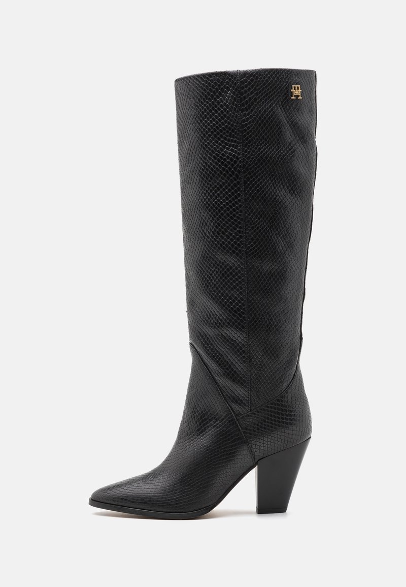 Black knee-high boots made of textured leather, featuring a pointed toe and a block heel, with a small gold logo on the upper side.