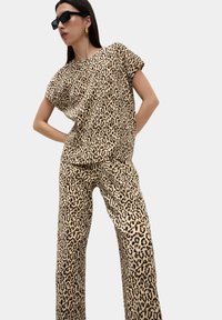 Set coordinato con stampa leopardata, realizzato in tessuto leggero. Il top presenta maniche corte; i pantaloni hanno un design a gamba dritta.