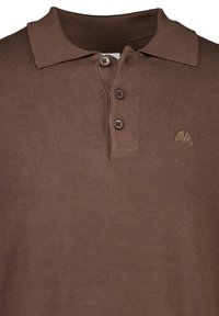 Ruskea neulottu polo-paita, jossa on ribbitaiteinen kaulus, kolme nappia sekä brodeerattu logo vasemmassa rinnassa. Pehmeä rakenne.