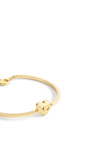 Bracciale dorato con un charm a forma di cuore liscio. Design a filo arrotondato, hardware minimalista e chiusura semplice.