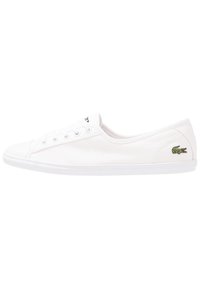 Baskets en toile blanches avec un bout rond, cinq œillets et un logo crocodile brodé vert sur le côté extérieur. Semelle en caoutchouc lisse.