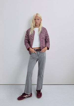 Chaqueta floral acolchada en tonos rosa y morado, camiseta corta blanca, jeans de pierna ancha grises y zapatillas burdeos con acentos blancos.