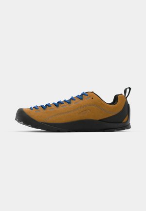 Brown suede outdoor shoe with blue laces, black rubber sole, and a sleek design. Features a rear pull tab for easy wear.