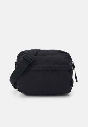 Borsa a tracolla nera realizzata in tessuto resistente con chiusura a zip, tracolla regolabile e texture liscia. Presenta un design minimalista.