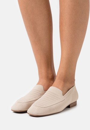 Mocassini beige realizzati in tessuto testurizzato, con tacco basso e punta appuntita, caratterizzati da sottili righe orizzontali sulla parte superiore.