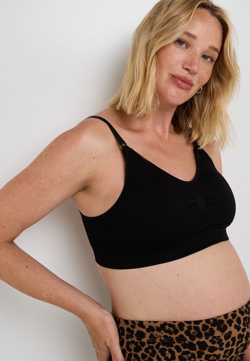 Bralette nera a costine con spalline regolabili e dettaglio frontale arricciato, abbinato a pantaloni a vita alta con stampa leopardata.