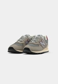 Scarpe da corsa grigie con tomaia in suede e mesh, caratterizzate da un logo bianco accentato, suola nera e dettagli rossi sul tallone.