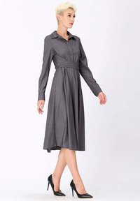 Robe à rayures grises avec un col, manches longues, et une taille ceinturée. Texture lisse, longueur genou avec une jupe légèrement évasée. Chaussures à talons hauts noires.