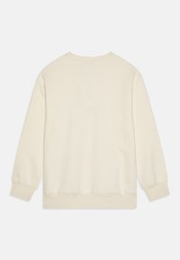 Krémová mikina s kulatým výstřihem a dlouhými rukávy. Má žebrované manžety a lem, hladkou texturu a žádné viditelné grafické detaily.