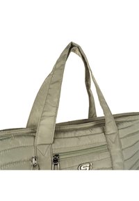 Bolsa tote acolchada verde con asas dobles, que cuenta con un bolsillo frontal con cremallera y costuras de acento. Hecha de un material suave y duradero.