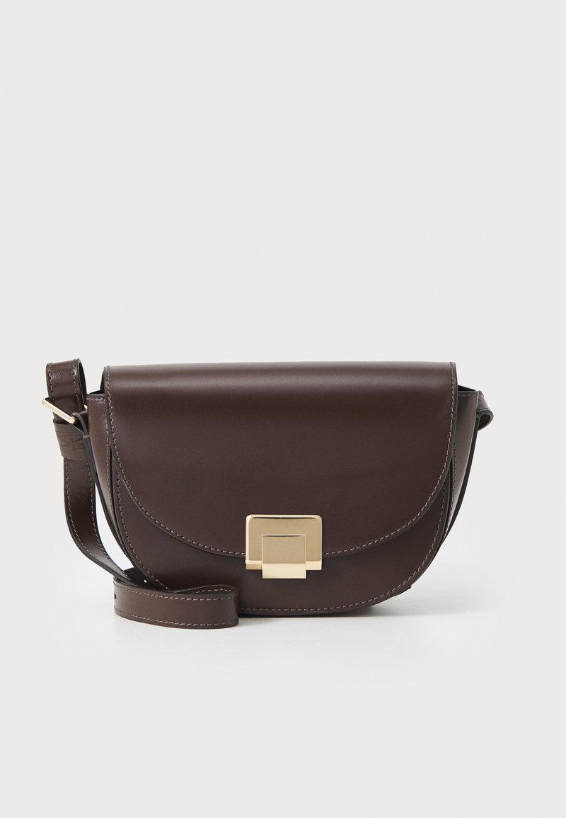 Sac en cuir marron à bandoulière avec un rabat arrondi, un fermoir carré en or et une sangle ajustable. Présente des détails de couture contrastants en ivoire.