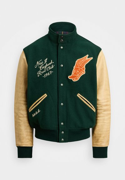 Veste varsity en laine verte avec des manches en cuir tan. Équipée d'un emblème ailé orange, d'un texte brodé et d'une fermeture à boutons-pression. Rayures contrastées sur les poches.