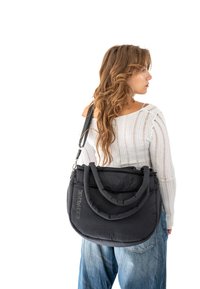 Black padded bag with dual handles and a detachable shoulder strap. Textured fabric, round shape, and a logo on the front.