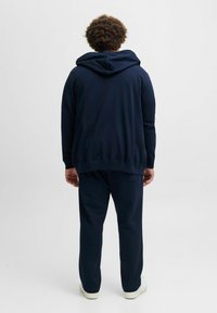 Marineblauwe hoodie en bijpassende sweatpants van zachte stof. Hoodie heeft een grote, verstelbare trekkoord en geribde manchetten.