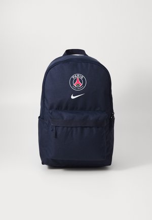 Tamsiai mėlyna kuprinė, pagaminta iš patvarios medžiagos, su priekinėje kišenėje užtrauktuku, Paryžiaus Saint-Germain logotipu ir baltais Nike swoosh simboliais.