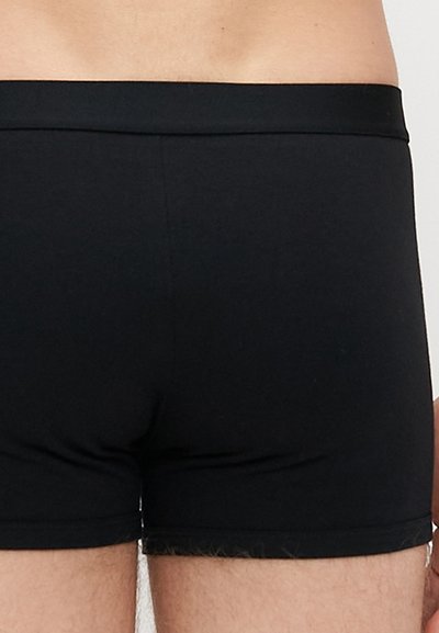 Boxer shorts pretos feitos de um tecido liso e elástico. Apresenta uma cintura ajustada e um corte de perna curto com detalhes texturais subtis.