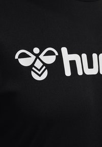 Sort stof med et hvidt bi-logo med stiliserede vinger og en geometrisk krop, samt ordet 'humb' i fede hvide bogstaver.