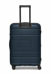 Valigia rigida blu con superficie testurizzata, maniglia nera retrattile e quattro ruote per la mobilità. Presenta dettagli curvi.