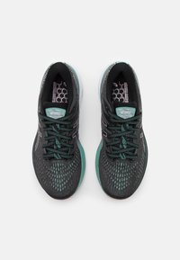 Chaussures de sport noires et turquoise avec tige en maille texturée, lacets contrastants et semelles à motifs. Présentent des accents réfléchissants et un logo.