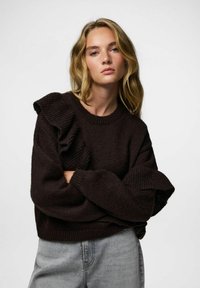 Ciemnobrązowy sweter dziany z falbanką na ramionach, fakturowaną tkaniną, długimi rękawami, szerokim okrągłym dekoltem i luźnym krojem.