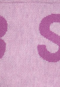 Textildecke in sanftem, blassem Lila mit großen, flauschigen, pinken Buchstaben. Die Textur ist plüschig und gewebt und hat einen subtilen Glanz.