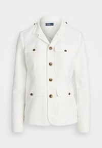 Vit jacka med en skräddarsydd passform, med snedkrage, två fickor med klaff och knappar i guldton. Tillverkad av ett slätt material med strukturerade sömmar.