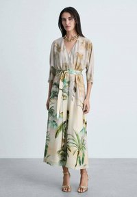 Abito lungo e morbido con stampa tropicale di palme in crema e verde, caratterizzato da un design avvolgente e una cintura coordinata in vita.