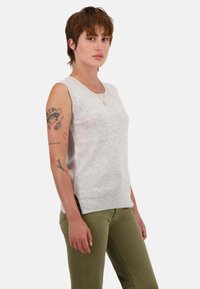 Hellgrauer �ärmelloser Pullover mit strukturierter Strickmusterung, geripptem Saum und klassischem Rundhalsausschnitt. Kombiniert mit olivgrünen Hosen.