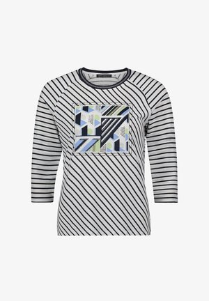 Haut à manches longues rayé blanc et marine, avec un patch de motif géométrique en bleu, vert et noir, col rond et manches raglan.