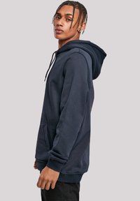 Navy blue hoodie made of soft fabric, featuring a front pocket, adjustable drawstring hood, and ribbed cuffs and hem.