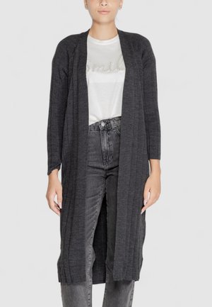 Cardigan lungo grigio scuro con texture a coste. Design aperto davanti, abbinato a una camicia bianca e jeans scuri a vita alta. Look semplice e versatile.