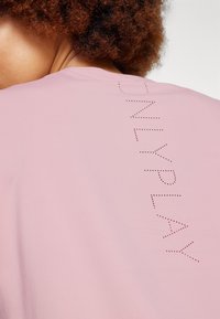 Pink athletic top with short sleeves, featuring dotted text "ONLYPLAY" along the back. Smooth texture, lightweight and casual design.