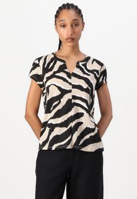 Kortærmet top i beige med sort-hvide zebra-striber, med V-hals og subtile syninger. Letvægts, vævet tekstur.