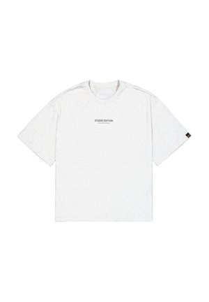 T-shirt blanc à manches courtes avec un col rond, présentant "STUDIO EDITION" imprimé en noir. Texture tricotée avec une coupe décontractée.