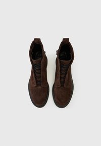 Bottines en suède brun avec une finition texturée, dotées de lacets et d'une fermeture éclair, accentuées par une semelle en caoutchouc noire.