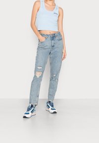 Ljusblå kort topp med ribbad textur; ihopparad med högmidjade ljusblå jeans med slitna hål och raka ben.