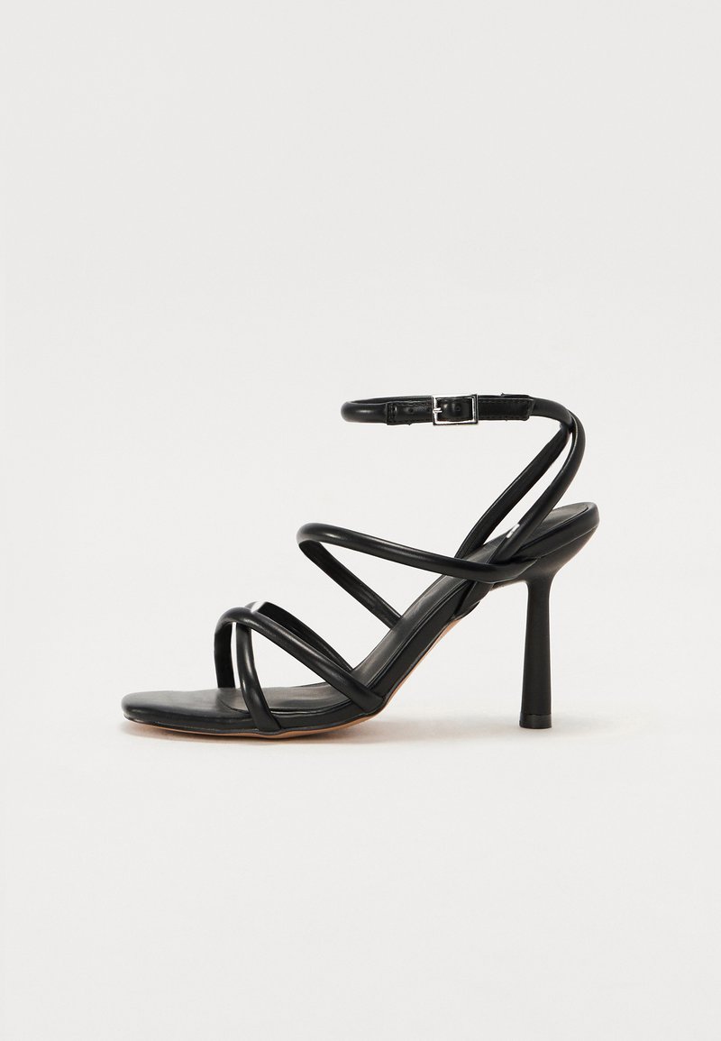 Sandal de salto alto preto com tiras finas entrelaçadas, fivela no tornozelo, textura de pele lisa e salto agulha afilado.