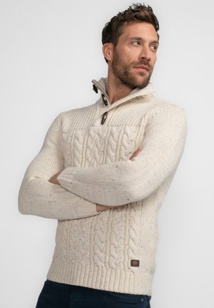 Pull en maille crème avec un motif en torsades, col zippé mi-hauteur, boutons en bois et poignets et ourlet côtelés. Le tissu présente des nuances subtiles.