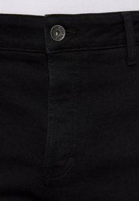 Schwarze Denim-Jeans mit einem Frontknopfverschluss, standardmäßiger Fünf-Taschen-Design und Nähdetails entlang der Nähte.