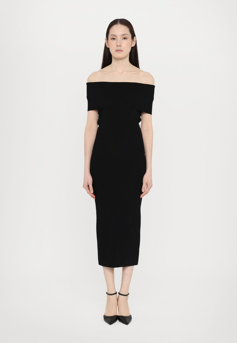 Black off-the-shoulder dress featuring a fitted silhouette, knee-length hem, and smooth, stretchy fabric. Paired with black pointed heels.
