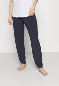 Marineblå, lätta bomullsnattbyxor med avslappnad passform, elastiska muddar och en jämn textur. Bärs med en enkel vit t-shirt.
