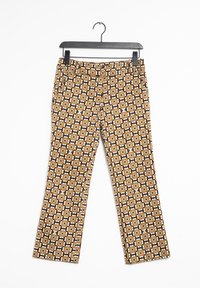 Spodnie z geometrycznym wzorem w brązowych, czarnych i kremowych kolorach. Materiał wydaje się tkaniną o gładkiej teksturze. Rozszerzany krój.